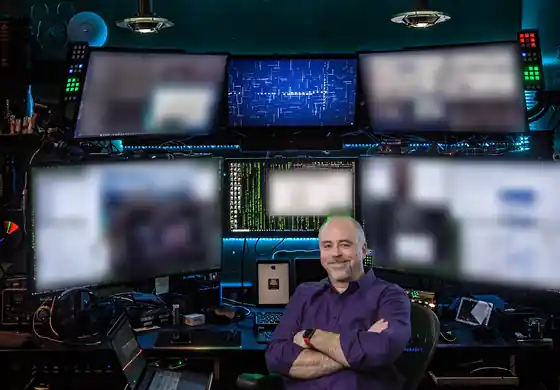 Chris Judd seated in front of a wall of monitors